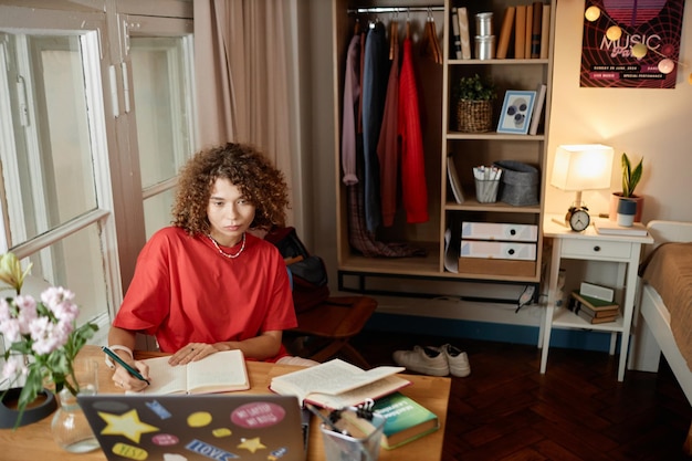 A student diligently studying test material in a well-lit, organized home study space, surrounded by textbooks, practice exams, and a digital tablet displaying study resources. The scene captures the essence of focused preparation.