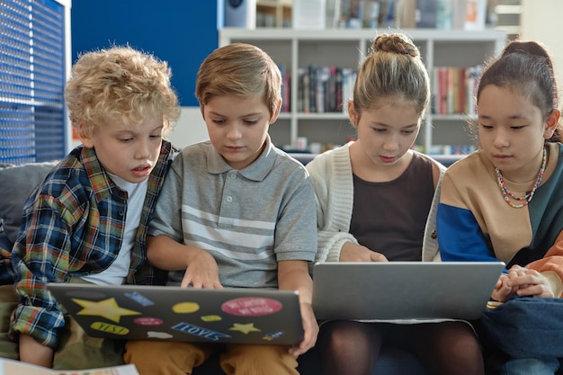 A group of elementary school children participating in a coding workshop, excitedly using tablets to learn basic programming concepts. The instructor is demonstrating a coding concept on a large screen.