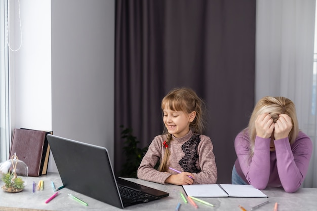 A child sitting at a desk struggling with a school assignment, with a concerned parent looking on, highlighting the need for parents to recognize and address their child's educational challenges.