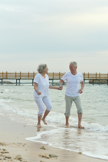 A serene image of an elderly couple enjoying their retirement, walking on a beach, symbolizing the rewards of planning and saving early.