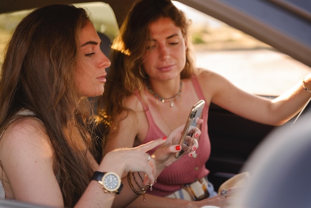 A close-up shot showing two colleagues sharing a ride, with one driving and the other navigating via a smartphone. The focus is on the cost savings and convenience aspects of carpooling.