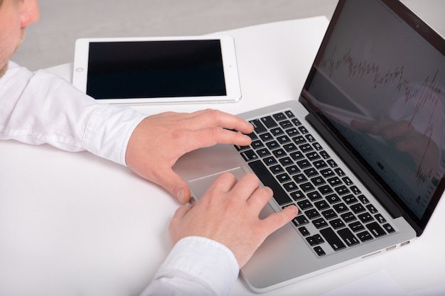 A close-up shot of hands typing on a laptop keyboard. The screen displays various graphs and charts related to retirement planning, showing calculations for different contribution scenarios to 401(k)s and IRAs. The overall mood is focused and professional.