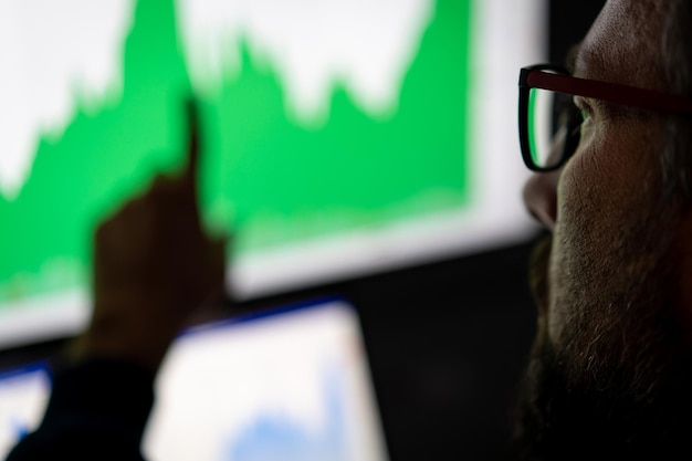 A close-up of a graph showing inflation rates spiking upwards, with a concerned investor in the background looking at a computer screen displaying stock market data.