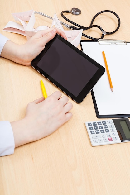 A person using a calculator and reviewing paperwork related to health insurance. The environment is a brightly lit office, with a focus on the individual's hands and the documents, suggesting a careful evaluation of healthcare costs.