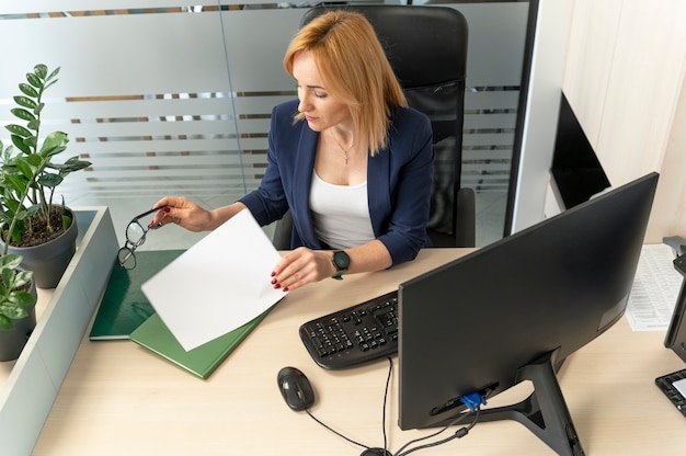 A person sitting at a desk, carefully reviewing documents related to an employee benefits claim. They are highlighting important sections and making notes.