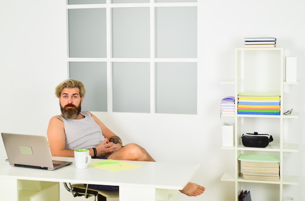A person is comfortably working from their home office, which is well-lit with a large window in the background. The focus is on the ergonomic setup including an adjustable chair and monitor stand, as well as the peaceful and productive atmosphere.