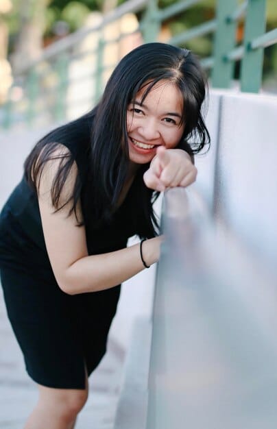 A close-up shot of a young Korean actress smiling dynamically at the camera, holding a clapperboard in front of her with 