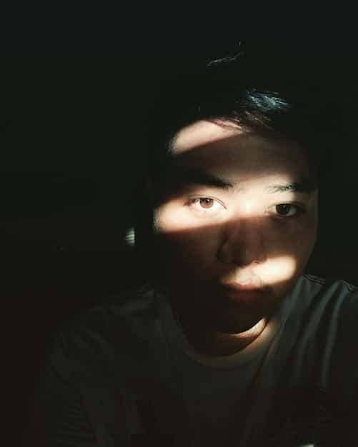 A close-up shot of a character's face in a Korean thriller, with a worried or frightened expression. The lighting is dramatic, with shadows emphasizing the tension.