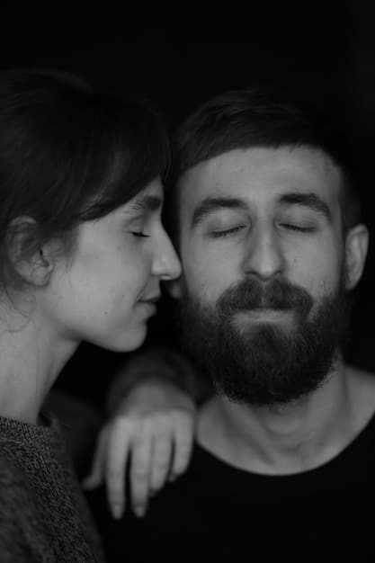 A grayscale image of a couple embracing tightly, their faces partially obscured, suggesting a sense of longing and desperation. The background is blurred, focusing attention on the emotional connection between the two individuals.