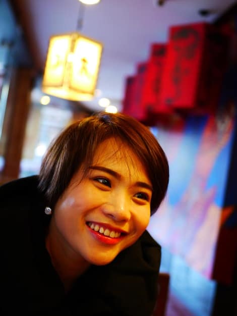 A close-up photo of a popular K-drama actor smiling and posing for the camera, with a bokeh background and warm lighting. Focus on his eyes and facial expression to convey warmth and charisma.