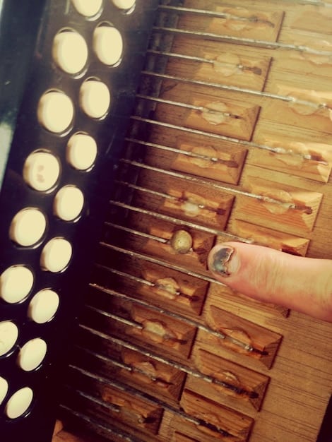 A close-up shot of a Mexican composer's hands skillfully playing a vintage synthesizer in a dimly lit recording studio. The focus should be on the details of the instrument and the composer's focused expression.