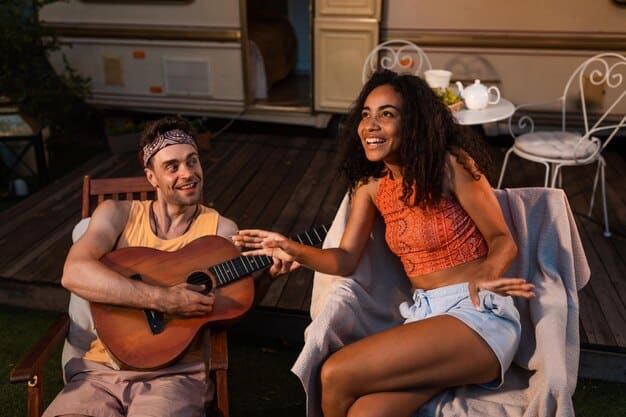 A Mexican film crew taking a break. A couple of crew members are sitting on folding chairs, drinking water and laughing. The sun is shining bright, but they are in the shade of a large film truck.