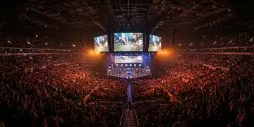 Packed esports arena with cheering fans and bright stage lights