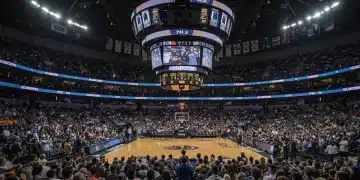 Packed NCAA championship arena with cheering fans and digital displays